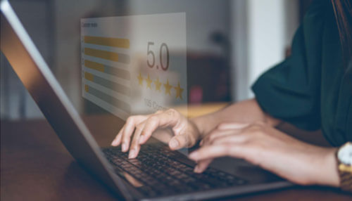 Respond to feedback and reviews A person typing on a laptop with a five-star rating displayed on the screen, symbolizing customer satisfaction and strong brand loyalty.