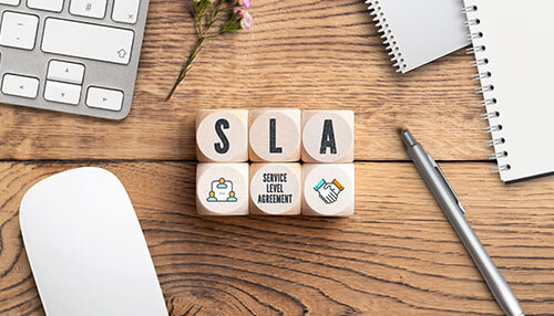 Service level agreement - tycoonstory | tycoonstory media Help desk software: a picture of the wooden blocks with letters "sla" on the desk with office items.