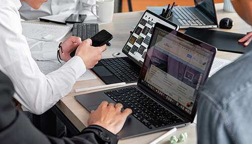 Use mobile devices Professionals working on laptops and smartphones during a team project discussion in an office setting