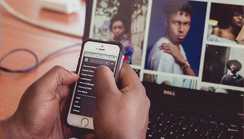 What are the benefits of doing reverse search image Close-up of a person using reverse image search on their phone while browsing images on a laptop screen.