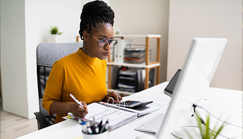 What to expect from an accountant A professional woman using a calculator and working with documents on her desk, representing accounting services and financial management.