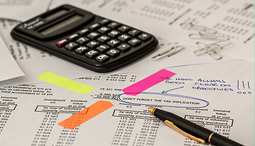 When must contractors who earn more than 0 in business income per year receive 1099 forms from you Financial documents with highlighted notes, calculator, and pen on a desk, illustrating tax preparation and filing 1099s for income reporting.