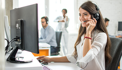 Customer service A customer service representative smiling while on a headset, demonstrating the importance of investing in customer service for your lending business.