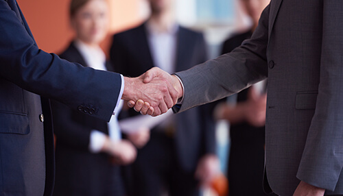 Pick the right partners Business professionals shaking hands, representing the partnerships and agreements crucial for successful international expansion.