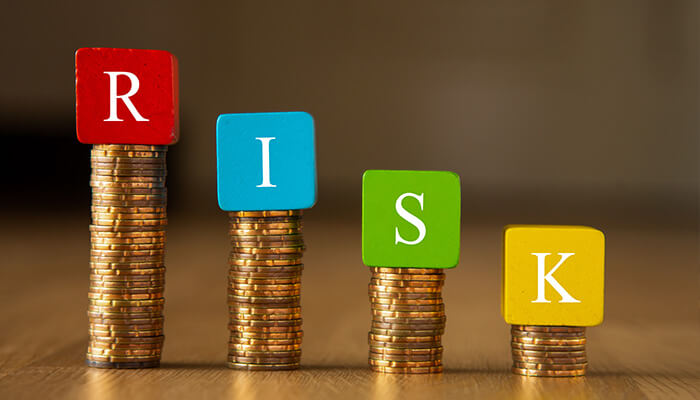 Financial risks - tycoonstory | tycoonstory media Stacked coins with colorful blocks spelling'RISK', representing financial risk management and investment decisions.