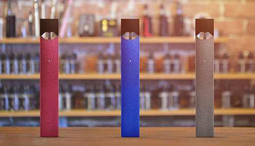 Vape shop Red, blue, and gray vape pens standing upright on a counter in a modern vape shop