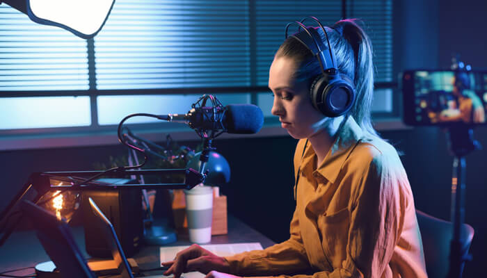 Invest in the filming equipment Female creator using a microphone and headphones while producing youtube videos.