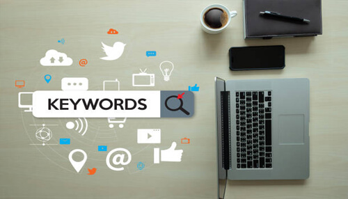 Add keywords Laptop with an image of social media icons and the word ‘keywords’ displayed, symbolizing keyword research and digital marketing.