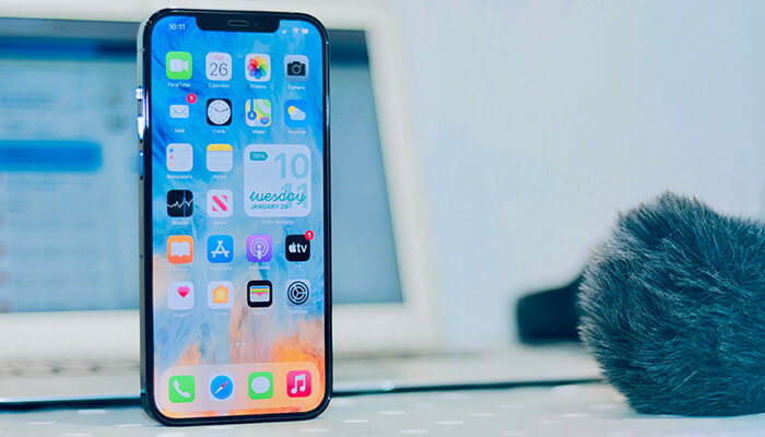 Latest smartphone Modern smartphone standing upright on a desk with blurred laptop in the background.