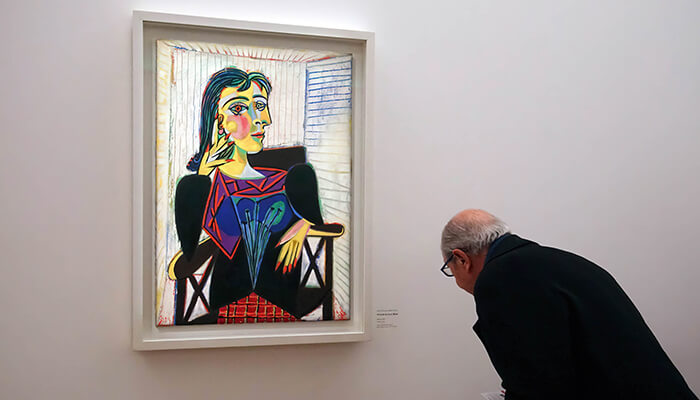 Mounting for 2d artwork A man observes a colorful modern artwork displayed in a gallery, beautifully presented in a perfect frame that enhances the artwork’s vibrant details.