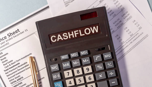 Cash flow statement A calculator with'CASHFLOW' written on it placed on top of financial documents, highlighting the importance of cash flow in financial statements.