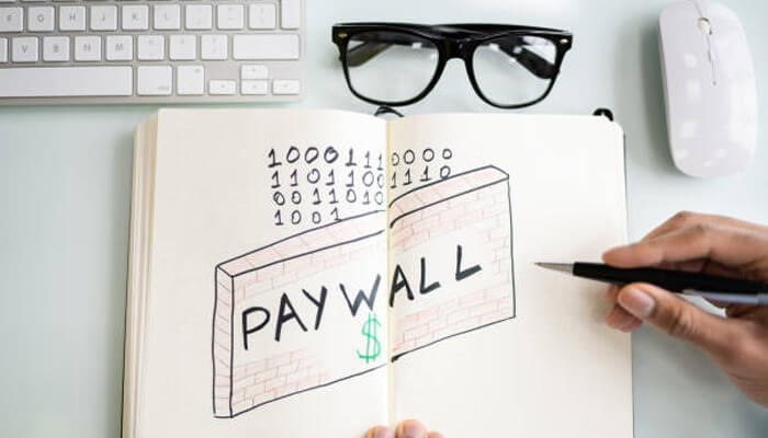 Added paywalls Hand drawing a “paywall” sketch with binary code and dollar sign in an open notebook on a desk