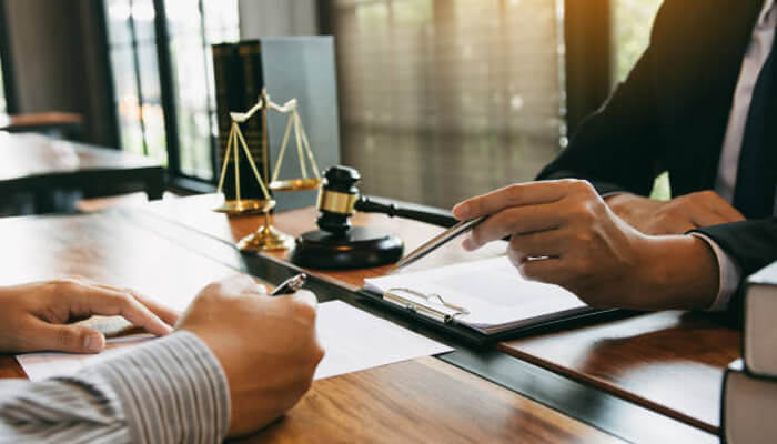 Conduct all communications about your accident through your attorney Lawyer discussing paperwork with a client in an office, representing legal help for victims harmed by defective products.