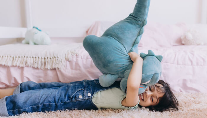 Giant stuffed animals - tycoonstory | tycoonstory media A child hugging a giant plush toy, smiling joyfully, with a baby tiger plushie among other stuffed animals, emphasizing the comfort and fun these toys bring.