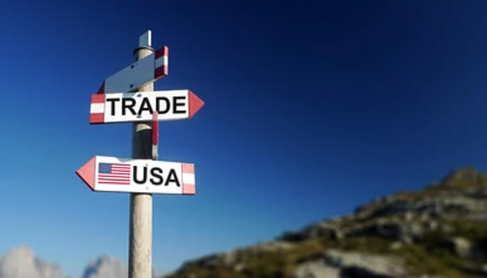 How should us policy look like in the year 2023 A signpost with arrows pointing to trade and "usa," set against a clear blue sky and mountains.