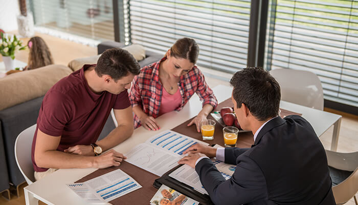 Why investing advice A financial advisor guiding a couple through financial planning documents at a table.