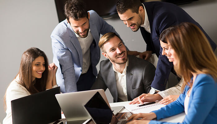 Tips for hiring a great management team A diverse group of professional lawyers or corporate executives posing for a formal portrait in a classic wood-paneled office with a library background.