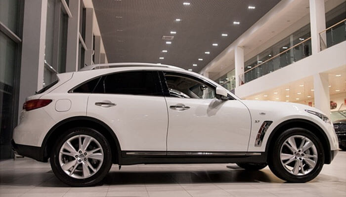 Use closing techniques Car sales showroom displaying a premium white suv ready for buyers
