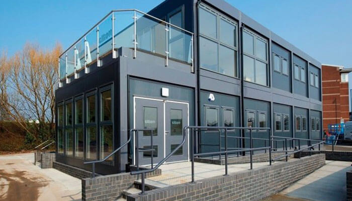 Refurbished modular building A modern, sleek modular building with glass windows and a staircase leading to the upper level, often used as a temporary or semi-permanent office space. Ideal for modular building applications.