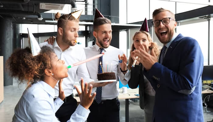 Great place to work Group of happy colleagues celebrating together with party hats and cake, exemplifying a fun and engaging atmosphere in a great place to work.