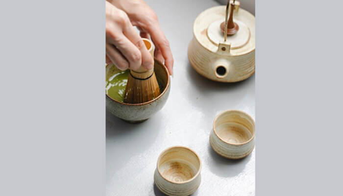 Mit45 extra strength shot A hand whisking green matcha powder in a ceramic bowl, showing natural ingredients often associated with mit45.