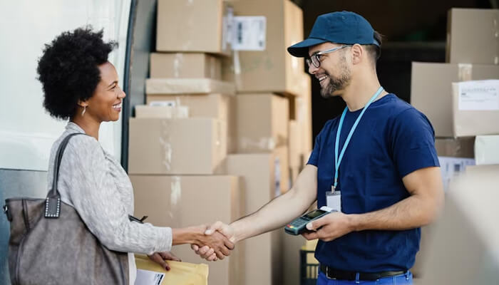 Partner with good suppliers A side-angle shot of a young digital entrepreneur in her home office celebrating a successful sale on her smartphone, surrounded by packaged shipping boxes and branded apparel for her gifting business.