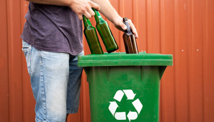 Recycling glass Person placing empty glass bottles into a recycling bin, highlighting sustainability in glass packaging