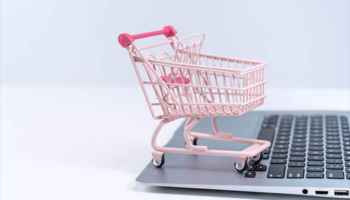 Rescue abandoned and empty carts Miniature pink shopping cart placed on a laptop keyboard, symbolizing the concept of retention marketing and rescuing abandoned online shopping carts.