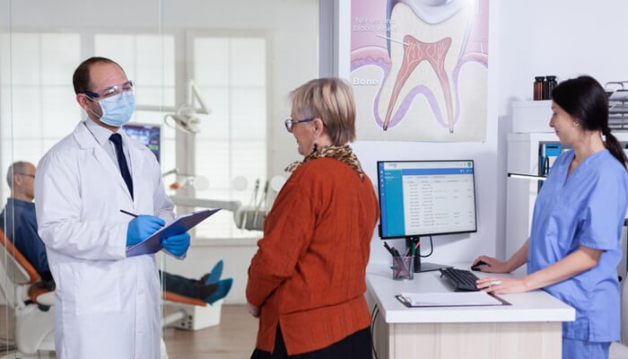 Dental reputation management A dentist and a patient interacting in a dental office, with a focus on customer service, representing the key aspects of managing a positive dental reputation.