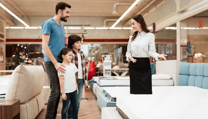 What to look for when shopping for an oversized mattress A family shopping for oversized mattresses in a store, discussing options with a sales associate to find the perfect fit.