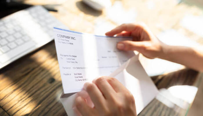 What are business checks Person opening a company check from an envelope — a practical example of why ordering checks for your business is essential for payroll and vendor payments.