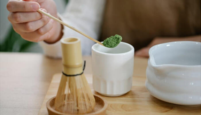 Why is leading premium coffee in the shot A hand measuring green powder with a bamboo spoon, showing precise dosage preparation related to mit45.