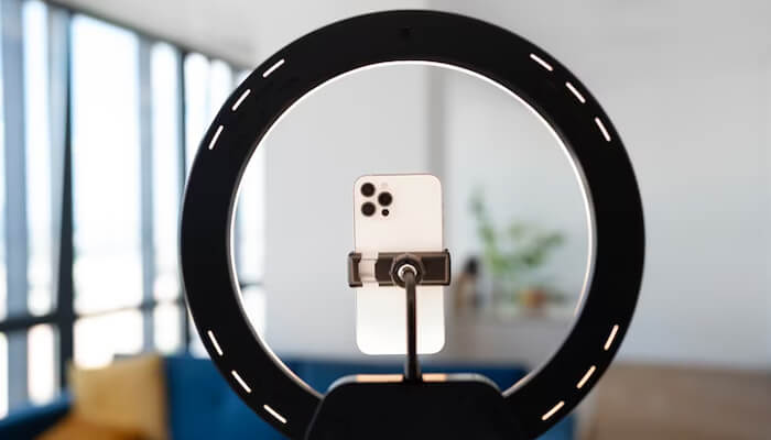 It is interactive Close-up of a phone mounted inside a ring light, set up for a professional-quality photo or video shoot, perfect for content creation.
