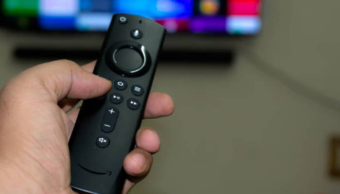Amazon firestick Hand holding a tv streaming remote while browsing a smart tv screen, representing easy access to entrepreneurial podcasts.