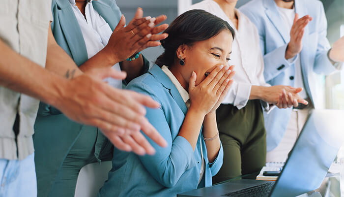 Encourage open communication A happy employee being applauded by coworkers, representing recognition and celebration in a people-centric workplace.