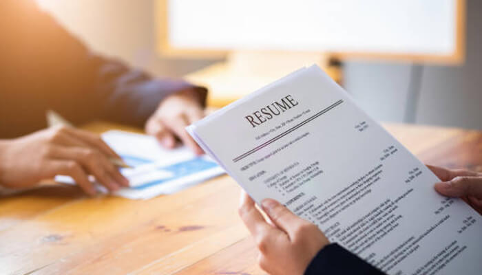 Experience A first-person perspective of a recruiter holding a professional cv over a wooden desk during an interview. The clean layout and clearly defined sections exemplify the standard formatting expected for a top-tier accounting resume in a corporate setting.