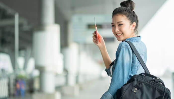 Foreign immigration is on the rise in china Young traveler at an airport terminal holding a passport and smiling, representing tourism and travel opportunities in china.