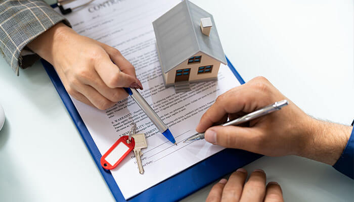 How do trust deeds work - tycoonstory | tycoonstory media Trust deed process illustrated by a property contract being signed with a house model and keys on the table, showing how a trust deed secures a real estate loan.