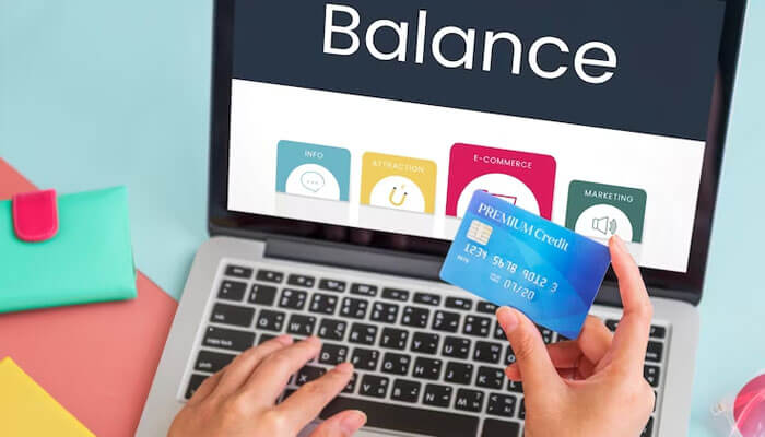 Keep credit card balances low Person checking credit card balance on a laptop screen while managing finances and improving credit score