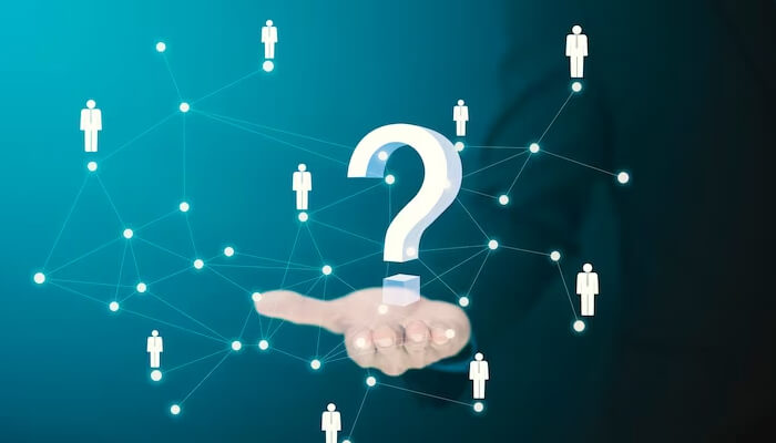 Know your audience - tycoonstory | tycoonstory media A hand holding a large, glowing 3d question mark surrounded by a network of connected person icons on a dark blue background.