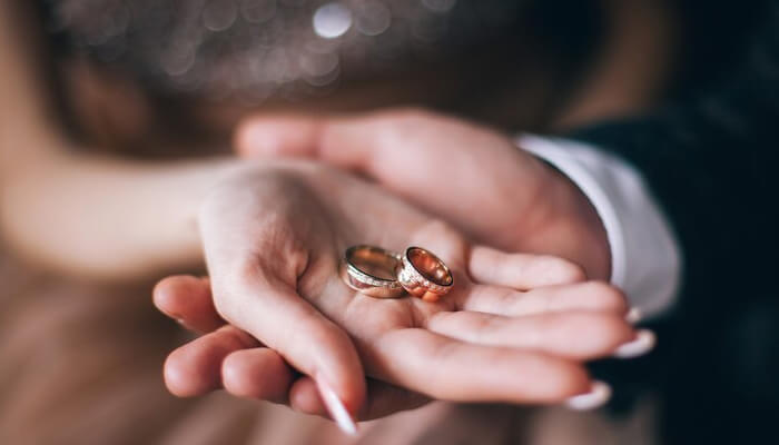 Modern engagement rings A close-up shot of two hands (one male, one female) gently holding a pair of traditional engagement rings or wedding bands in their palms. One ring is yellow gold, and the other is rose gold, both set with small diamonds. Would you like alt text for any other images, or do you have a different focus keyword you'd like to use