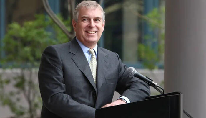 Prince andrew Prince andrew smiling at a podium, with harry and meghan's story making headlines in the background of royal family tensions.