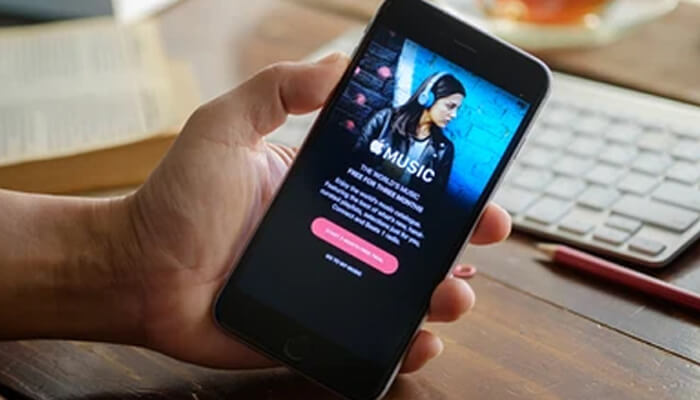 Promote your music via the itunes chart Person holding a smartphone displaying an apple music subscription screen, illustrating streaming engagement and itunes chart promotion efforts.