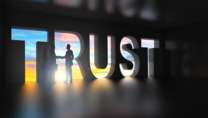 What can you achieve with trust People shaking hands inside large trust letters symbolizing transparency, confidence, and the importance of a living trust in estate planning.