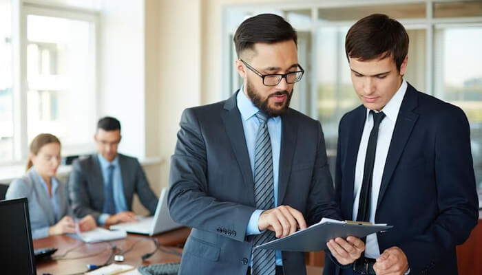 Why do you want to initiate a business Two professionals reviewing documents in an office, demonstrating leadership and entrepreneurial mindset.