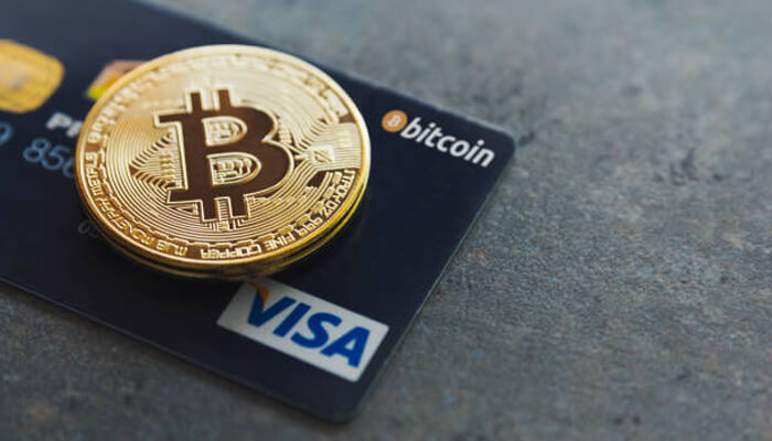 Binance card Golden bitcoin coin placed on a visa debit card representing digital payments using a binance card.