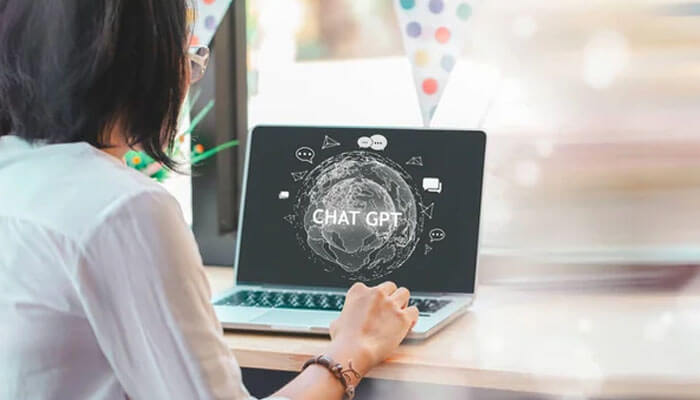 Chatgpt-tycoonstory | tycoonstory media A person sitting at a laptop, with a globe-like design featuring chatgpt icons on the screen, showcasing a digital workspace