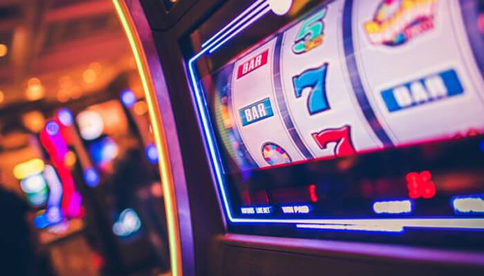 Choose-slots-with-a-suitable-bet-size-for-your-bankroll-tycoonstory | tycoonstory media Playing slots on a brightly lit casino slot machine showing bar symbols and sevens on the reels