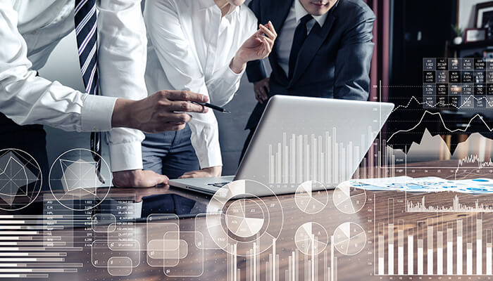 Collect data from focus groups or surveys Business professionals reviewing data on a laptop, surrounded by transparent, futuristic overlays of charts, graphs, and circular data in a market research setting.