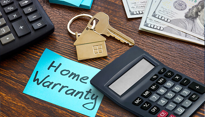 How-much-does-a-home-warranty-cost-tycoonstory | tycoonstory media Home warranties: a calculator, house key, and money alongside a sticky note with'Home Warranty' written on it.